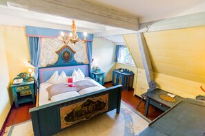 A bedroom with a bed, a chandelier, a nightstand, and a dresser. - Hotel Schloss Leonstain (Poertschach am Woerthersee)