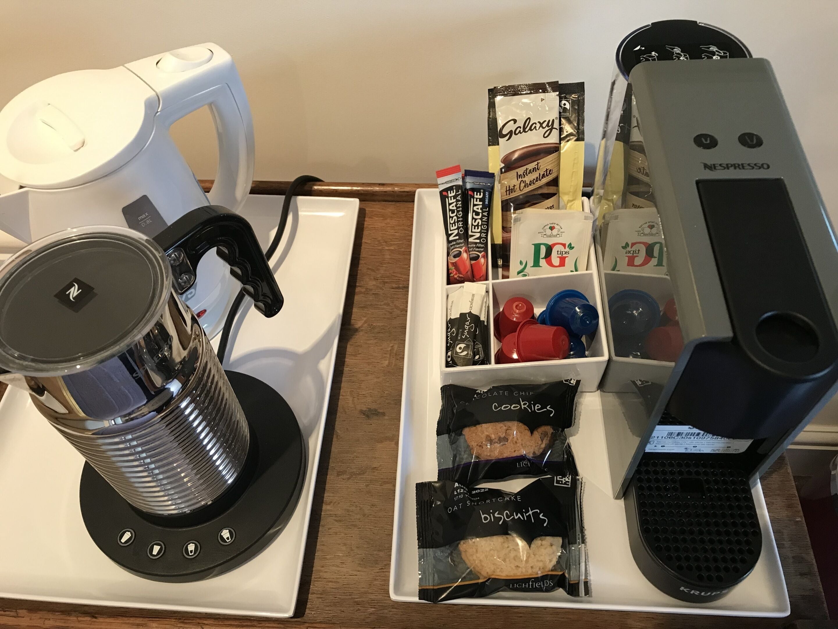 A coffee machine, a kettle, and a tray with various coffee pods and snacks.