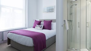 A bedroom with a bed, a shower, and a window. - Brighton Marina House Hotel (Brighton)