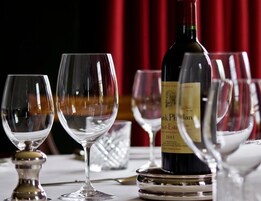 Una botella de vino sobre una mesa con varios vasos de vino vacíos.