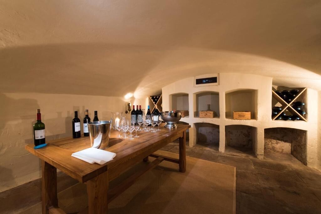 A wine cellar with a wooden table, wine bottles, glasses, and a wine rack.