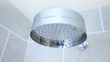 A showerhead with a perforated design, mounted on a wall with a tiled surface.