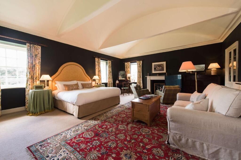 Una habitación de hotel con una cama grande, un sofá, una mesa de centro y una chimenea.