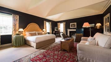 Una habitación de hotel con una cama grande, un sofá, una mesa de centro y una chimenea.
