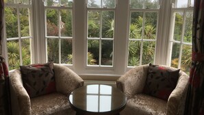 A room with a large window, two armchairs, and a small table. - The Charterhouse (Torquay)