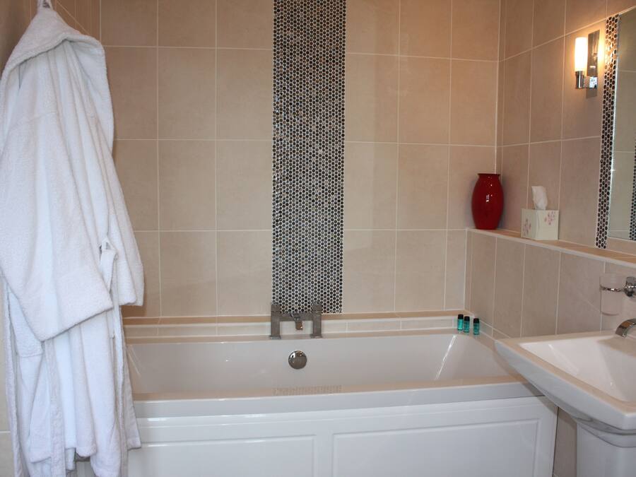 A bathroom with a bathtub, a sink, and a towel rack.