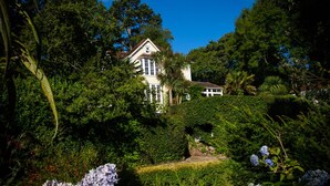 A large, white building surrounded by lush greenery and trees. - The Charterhouse (Torquay)