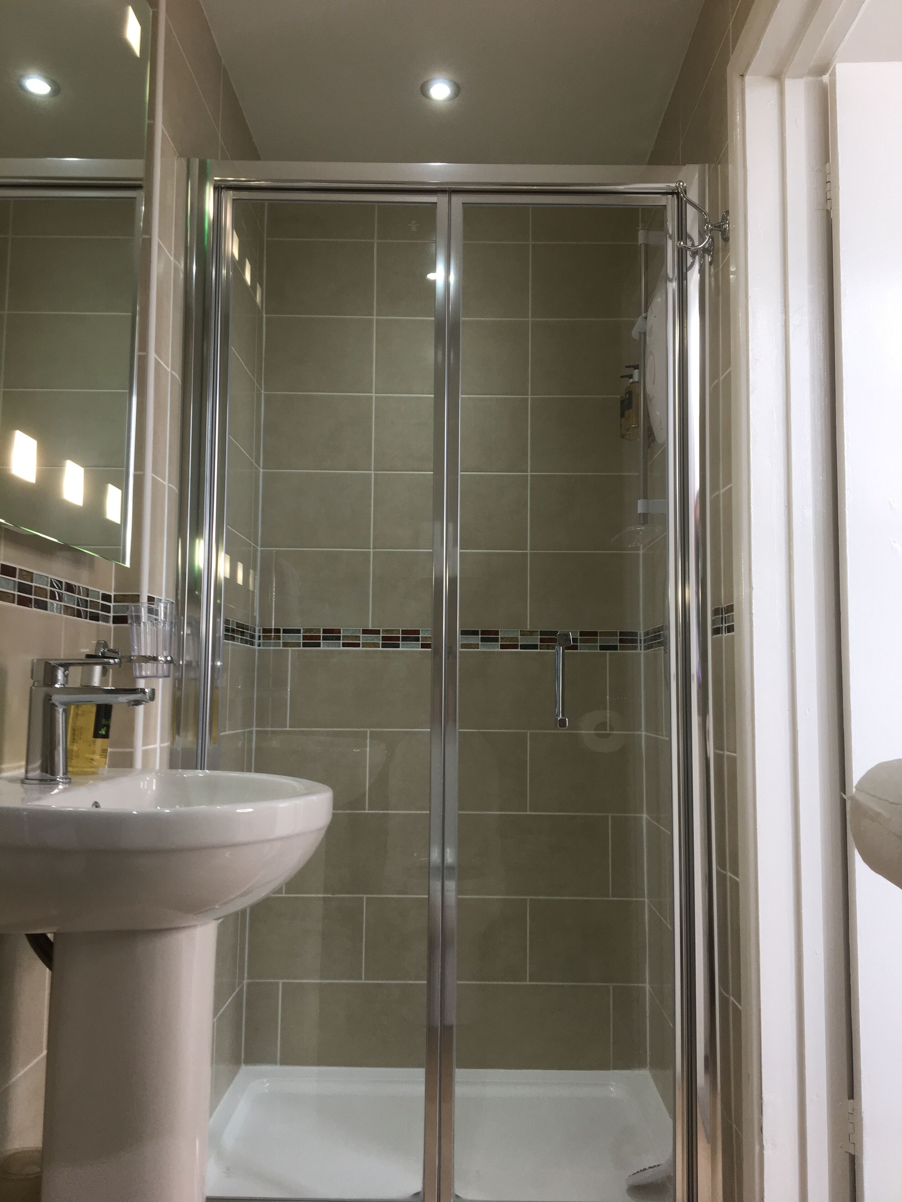 A bathroom with a glass-enclosed shower, a sink, and a mirror.