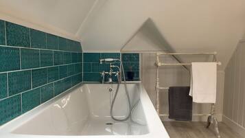Un baño moderno con una bañera independiente, un perchero y baldosas teal con diseño en las paredes.