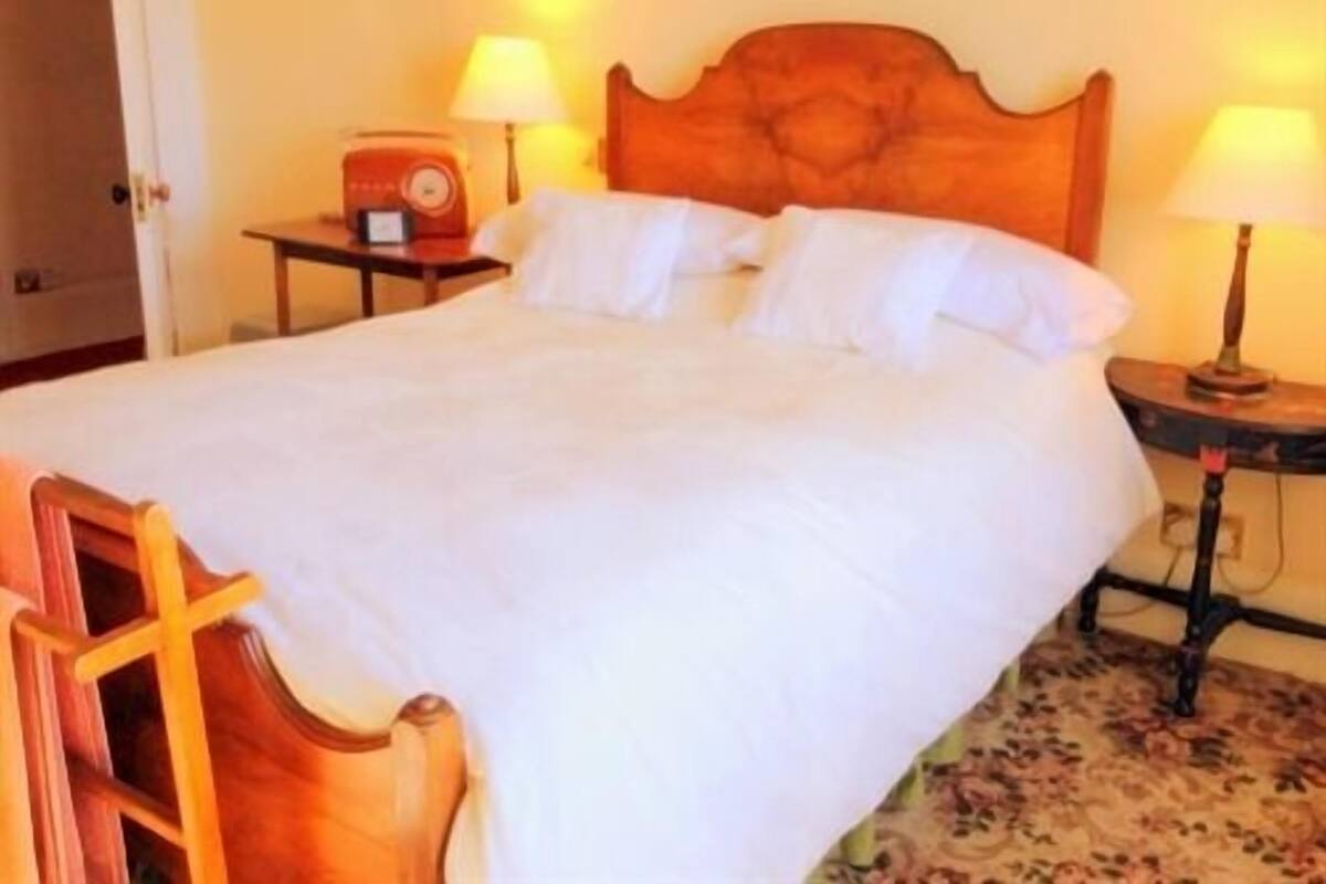 A hotel room with a large bed, two bedside tables with lamps, and a wooden headboard.
