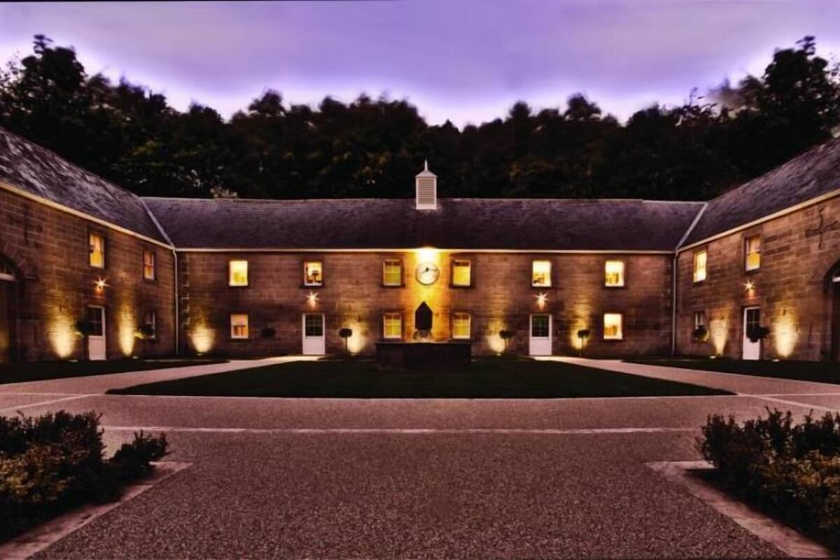 A large, symmetrical building with a central courtyard, evenly spaced windows, and a clock on the facade.