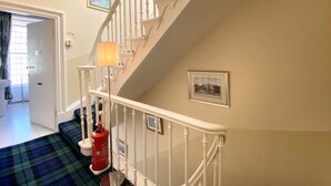 A staircase with white balusters and a red fire extinguisher on the landing. - Daviot House (Ayr)