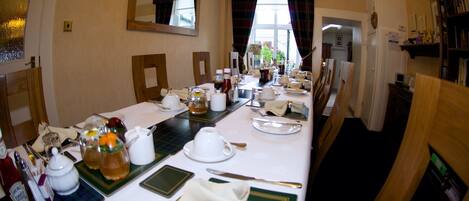 A dining room with a long table set for a meal, including plates, cutlery, and glasses.