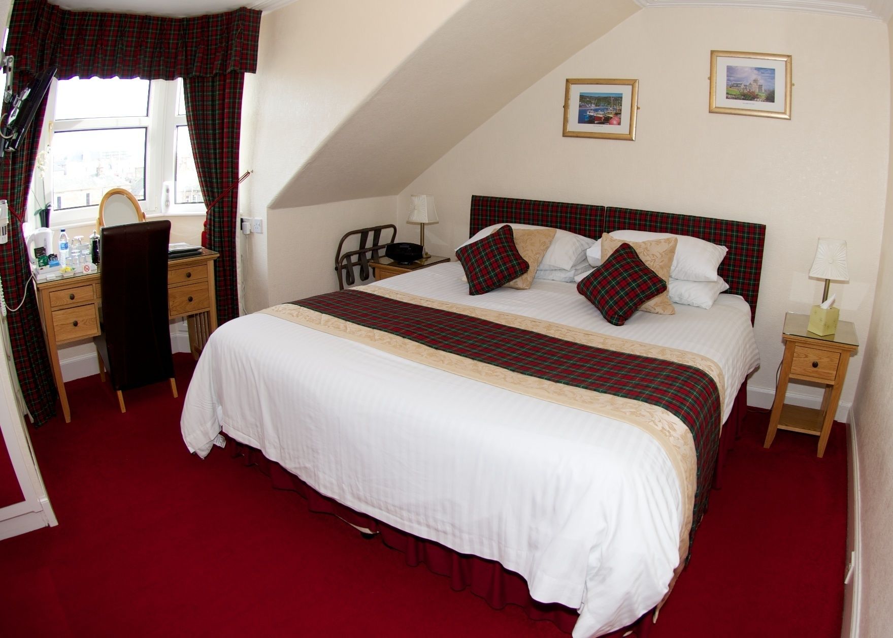 A neatly arranged bedroom with a large bed, a desk with a mirror, and two bedside tables.
