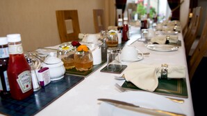 A dining table set with various condiments, a teapot, and a pitcher of tea, indicating a self-service breakfast setup. - Daviot House (Ayr)