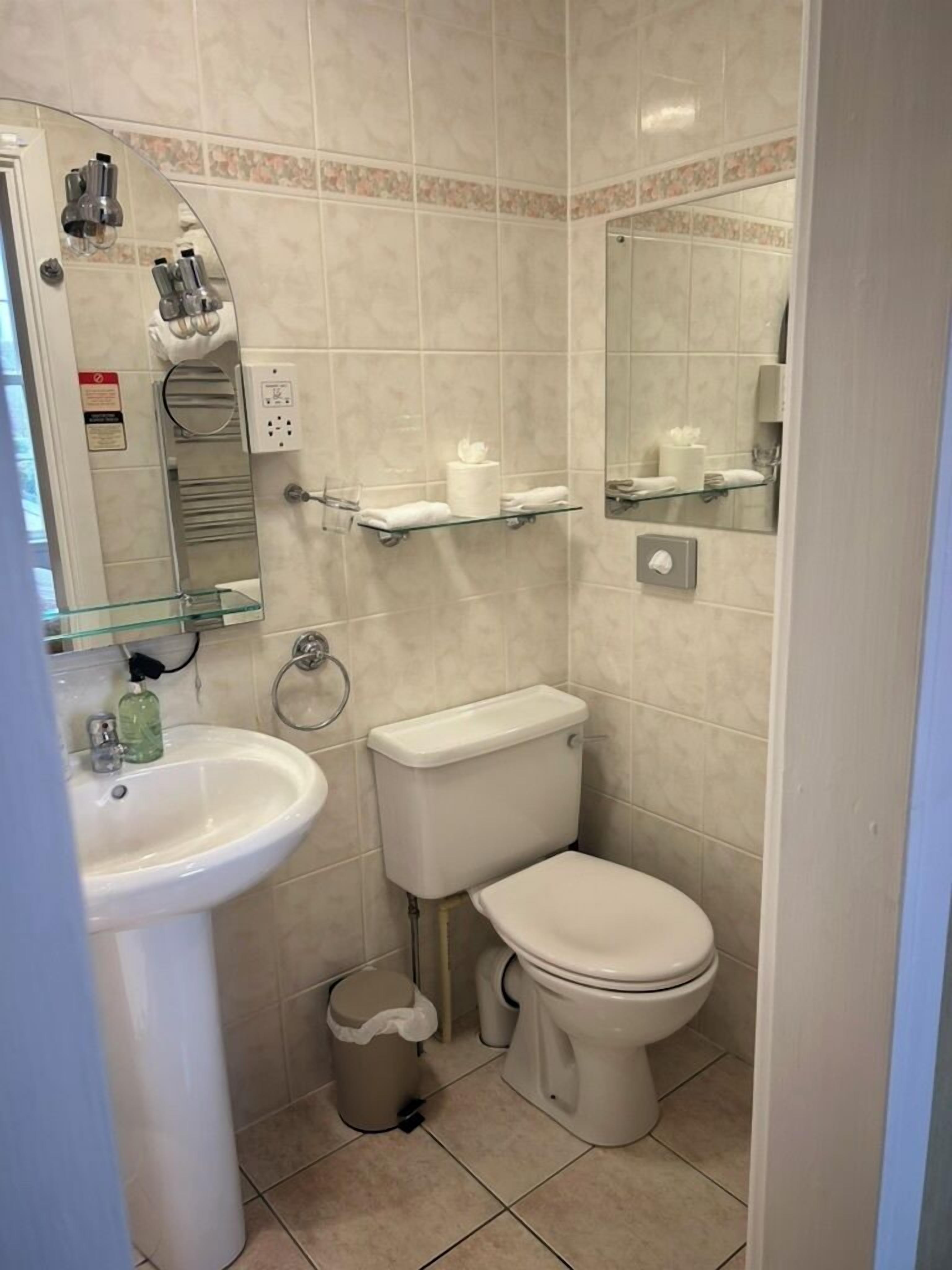 A bathroom with a sink, toilet, and glass shelves.