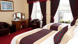 A hotel room with two beds, a desk, a chair, a dresser, and a window with curtains. - Daviot House (Ayr)