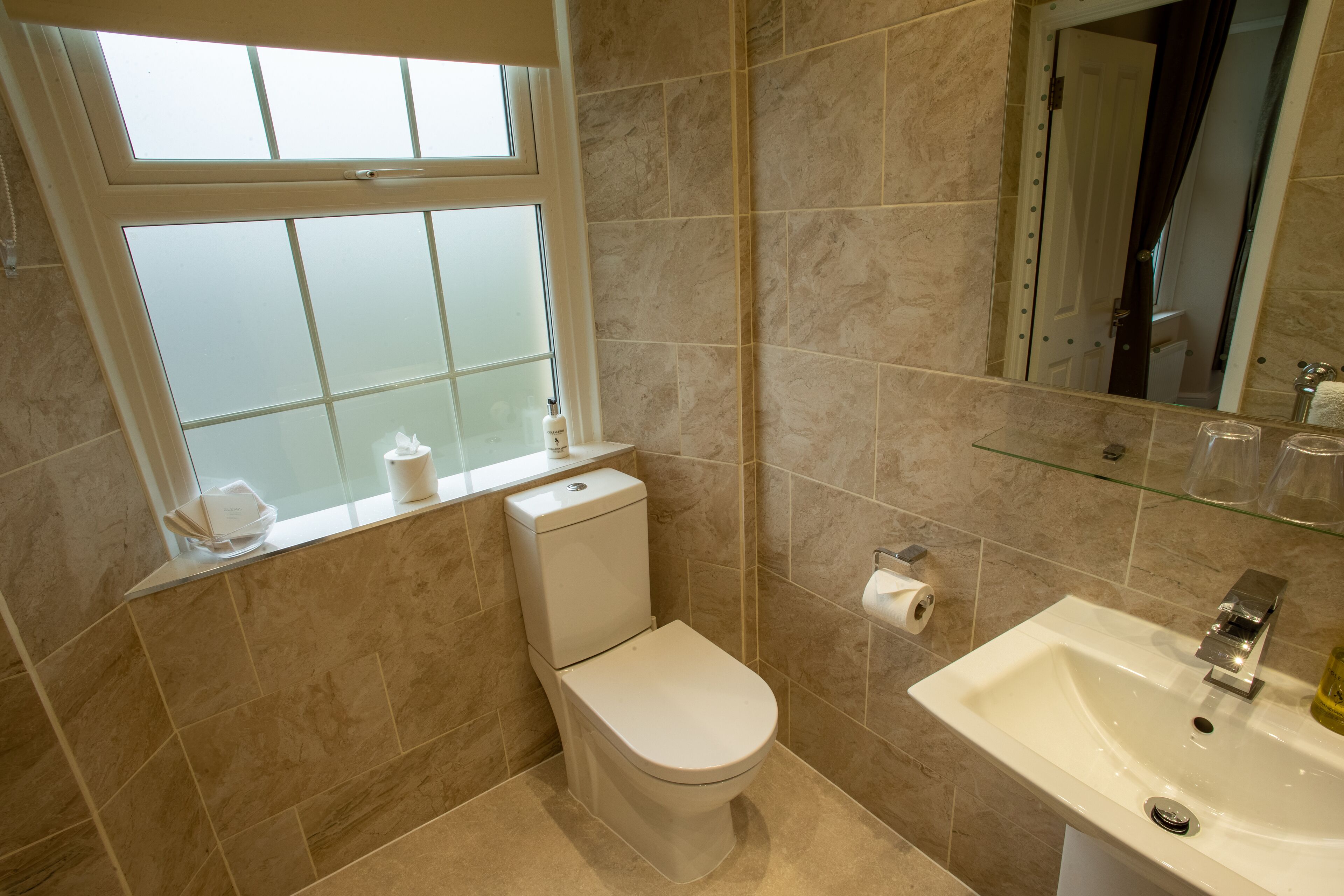 A bathroom with a toilet, sink, and a window with frosted glass.