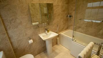 A modern bathroom with a white sink, a glass-enclosed shower, and a bathtub.