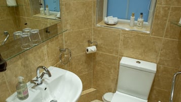 Un baño con lavamanos, inodoro y ventana sobre el inodoro.