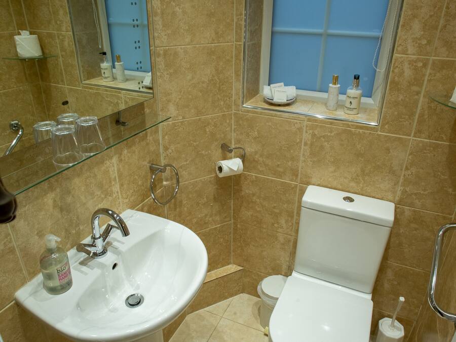 Un baño con lavamanos, inodoro y ventana sobre el inodoro.