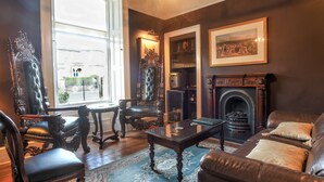 A traditional living room with a fireplace, leather furniture, and framed artwork. - Glenalmond Guest House (Edinburgh)