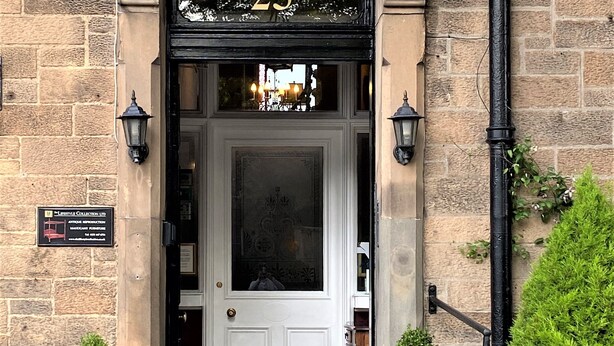 The entrance to Glenalmond House, featuring a stone facade, a white door with a glass panel, and two potted plants at the entrance. - Glenalmond Guest House (Edinburgh)