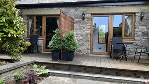 A stone building with a wooden deck, two potted plants, and outdoor furniture. - Glenalmond Guest House (Edinburgh)