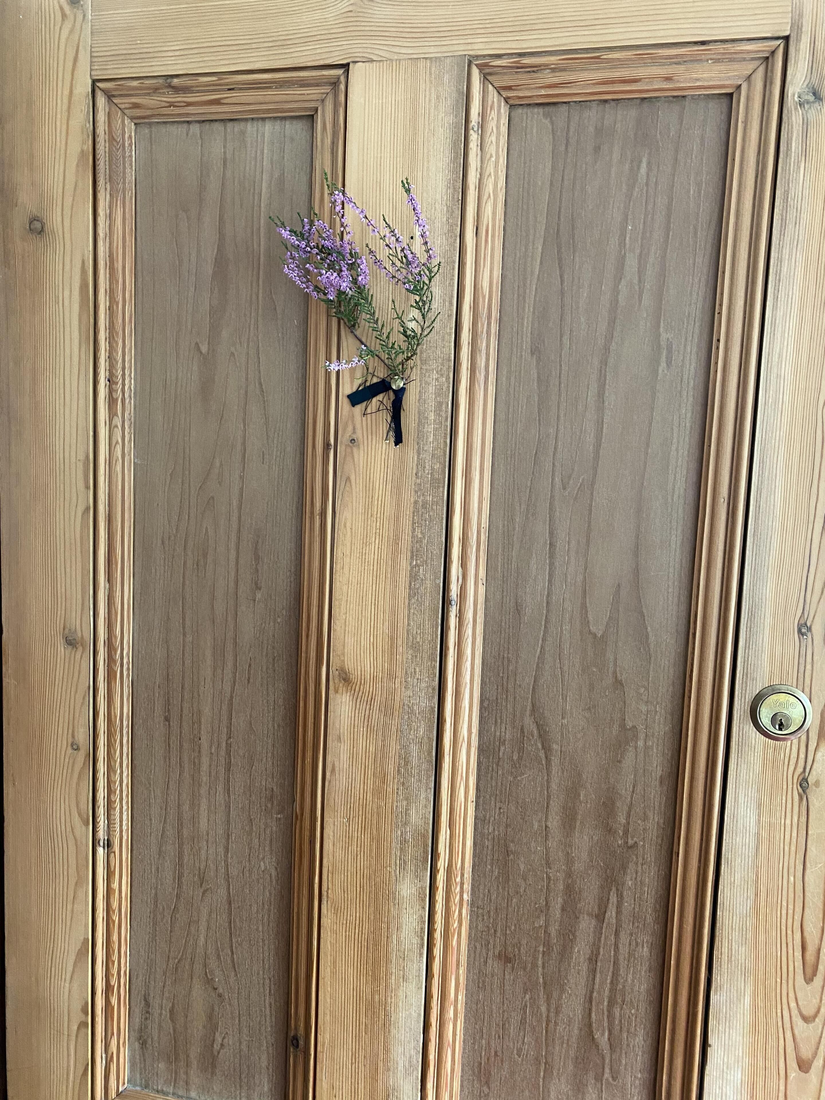 A wooden door with a keyhole and a decorative floral arrangement.