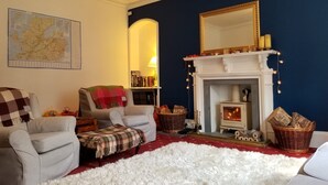 Un salon chaleureux avec une cheminée, une carte accrochée au mur et un mur d’accent bleu.