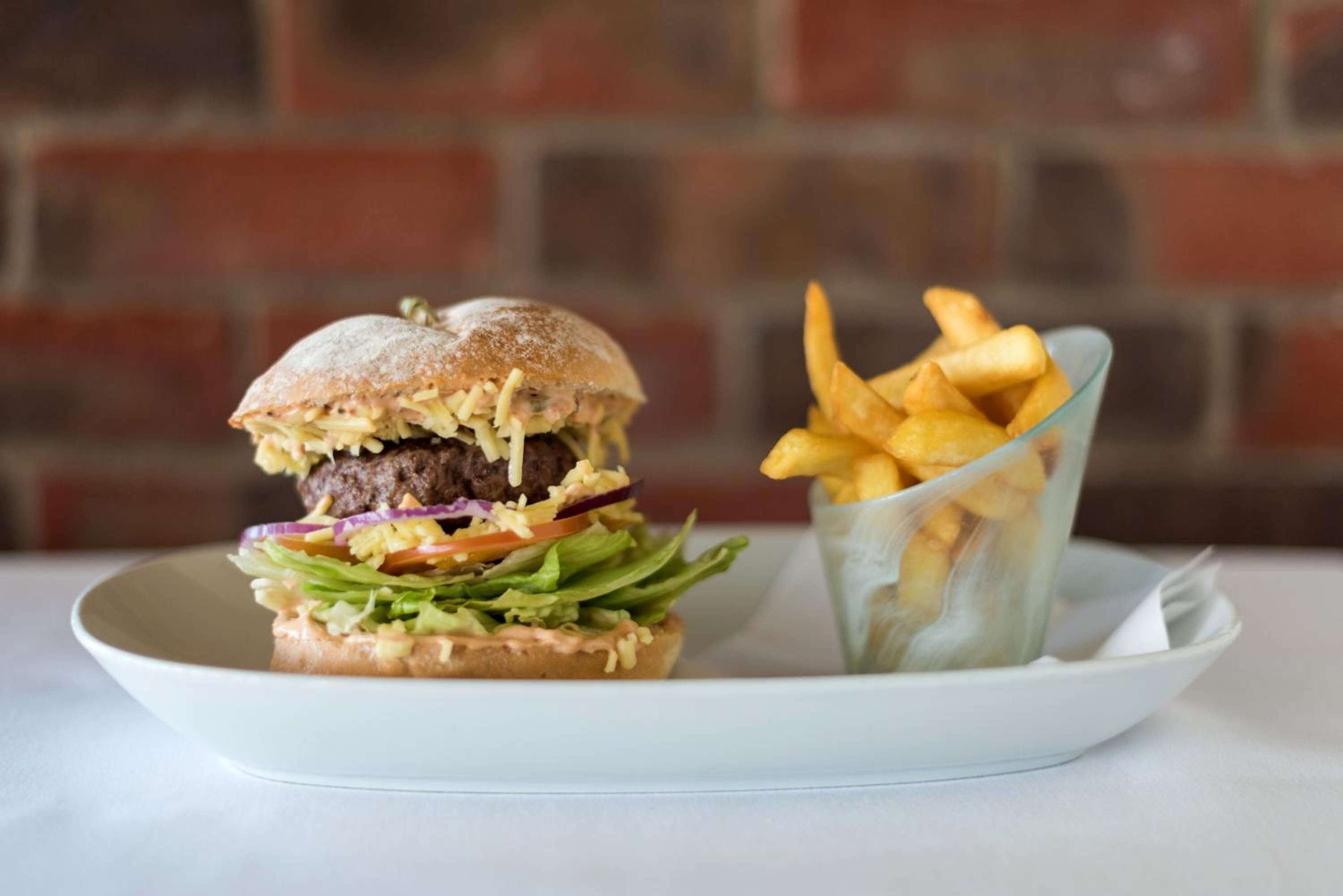 A burger with fries on a white plate.