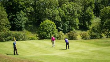 Un campo da golf con tre giocatori in diverse posizioni.