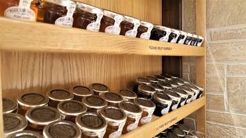 A wooden shelf with jars of honey and blackcurrant jam.