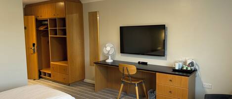 Ein Hotelzimmer mit Bett, Schreibtisch mit Stuhl, Fernseher und Kleiderschrank.