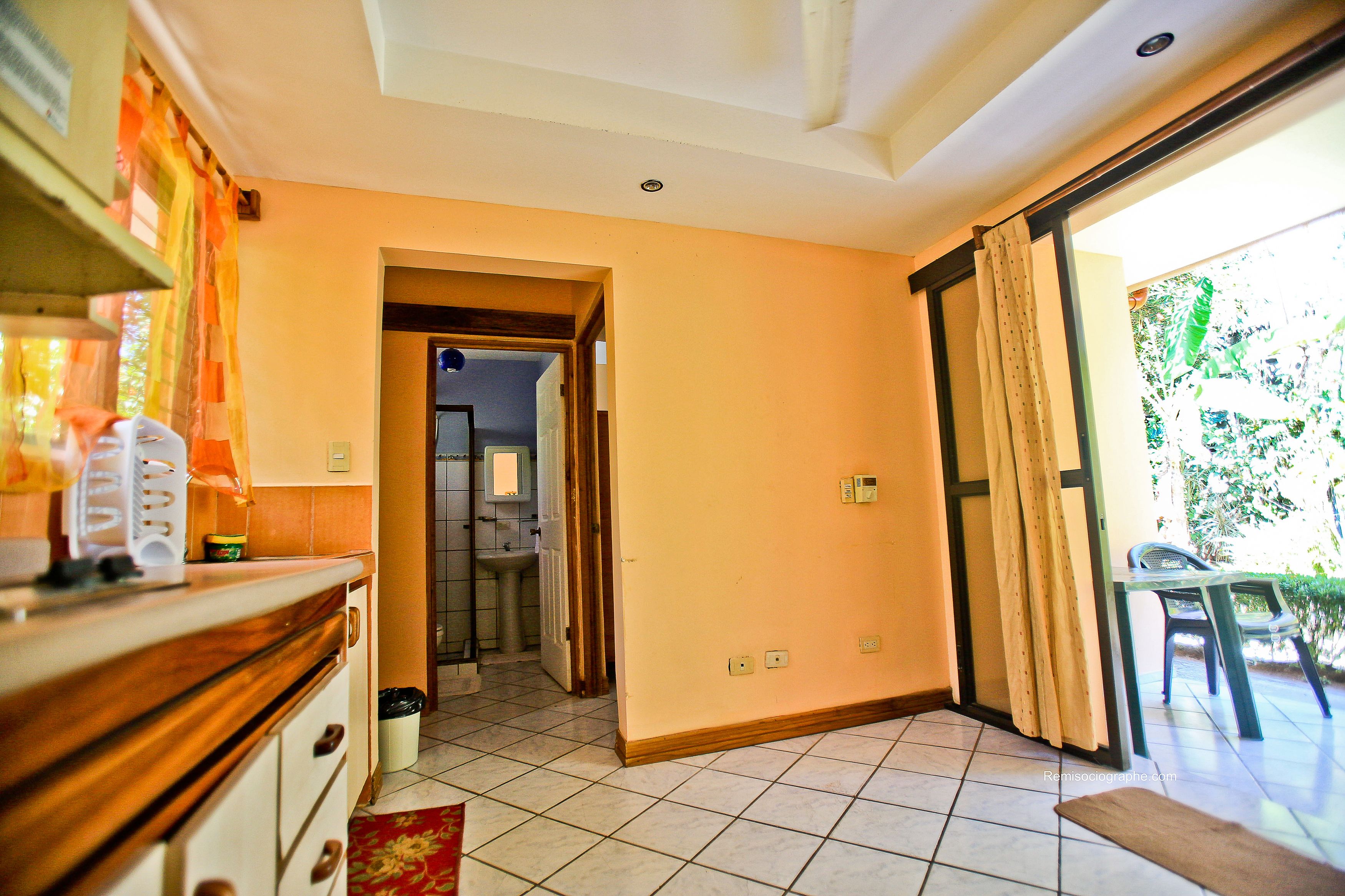Habitación con cocina, baño y balcón con vistas a zonas verdes.