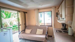 A room with a sofa, a small table with a coffee maker, and a window with curtains. - Hotel La Dolce Vita (Parrita)