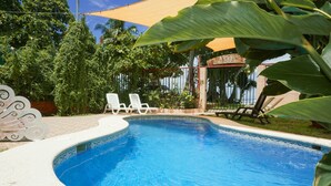 A swimming pool with white lounge chairs and a covered area with a sign reading "LA DOLCE". - Hotel La Dolce Vita (Parrita)