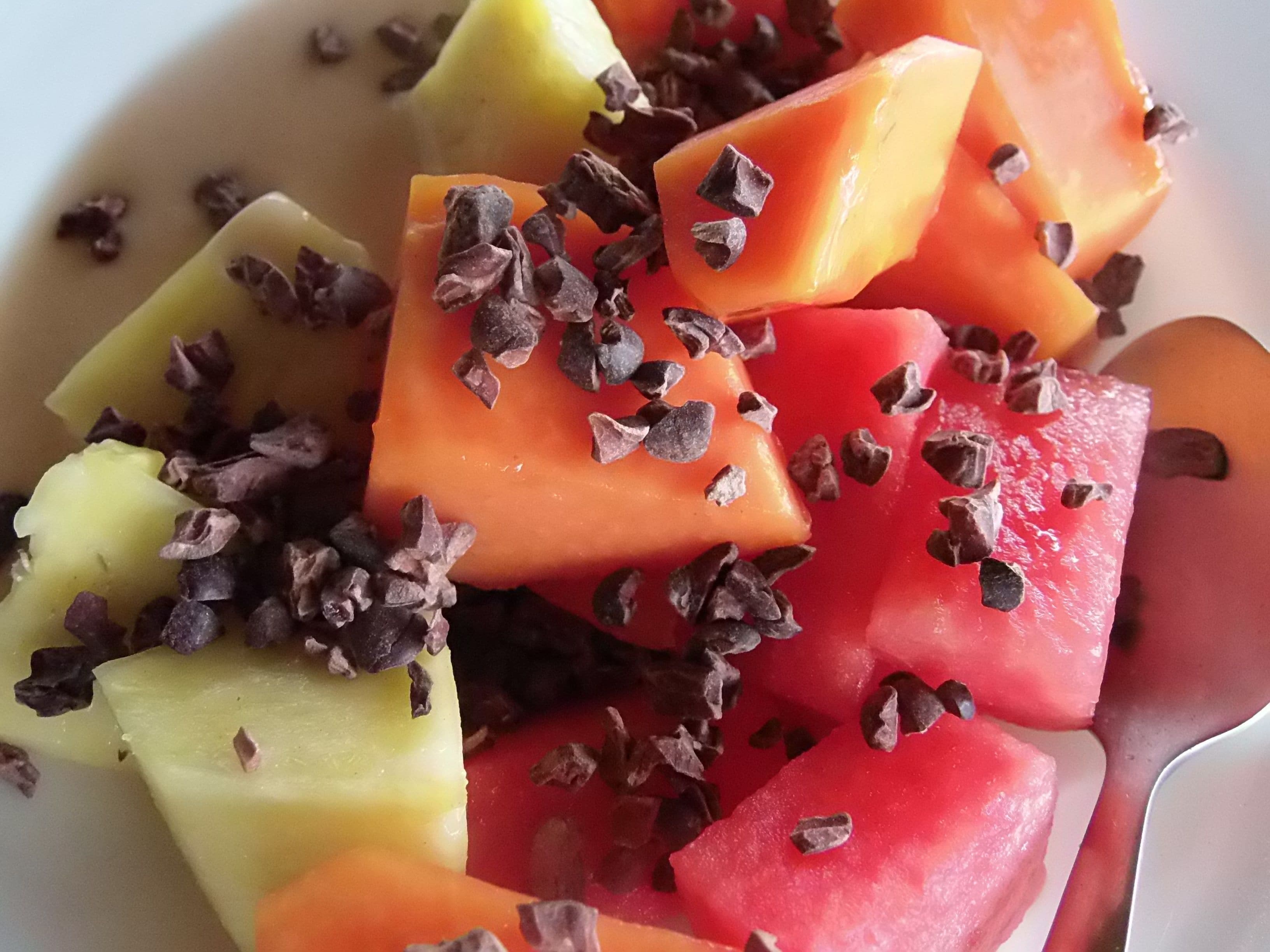 Uma tigela de salada de frutas com pedaços de melancia e melão, polvilhada com gotas de chocolate.
