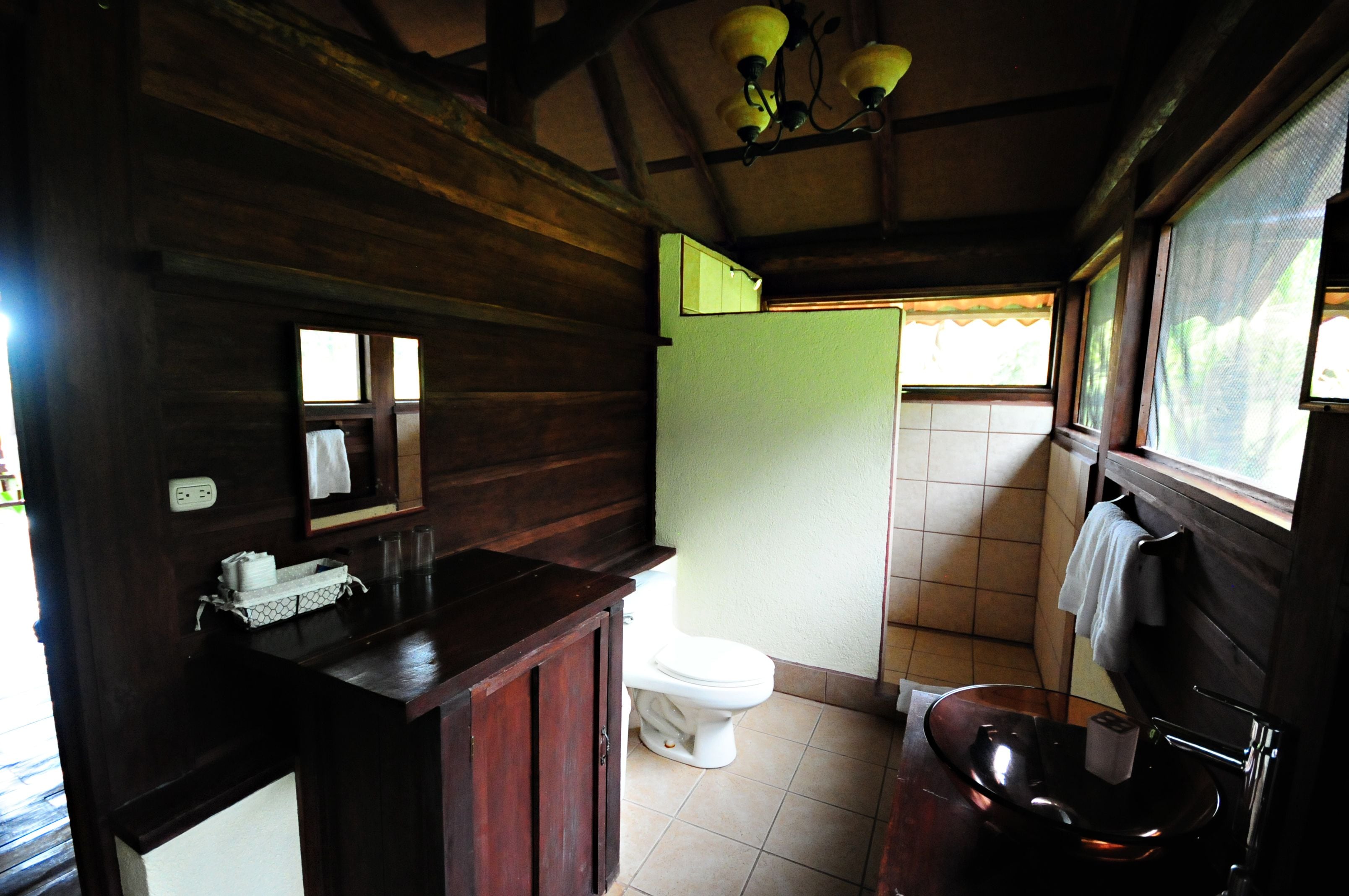Une salle de bain en bois avec des toilettes, un lavabo et un miroir.