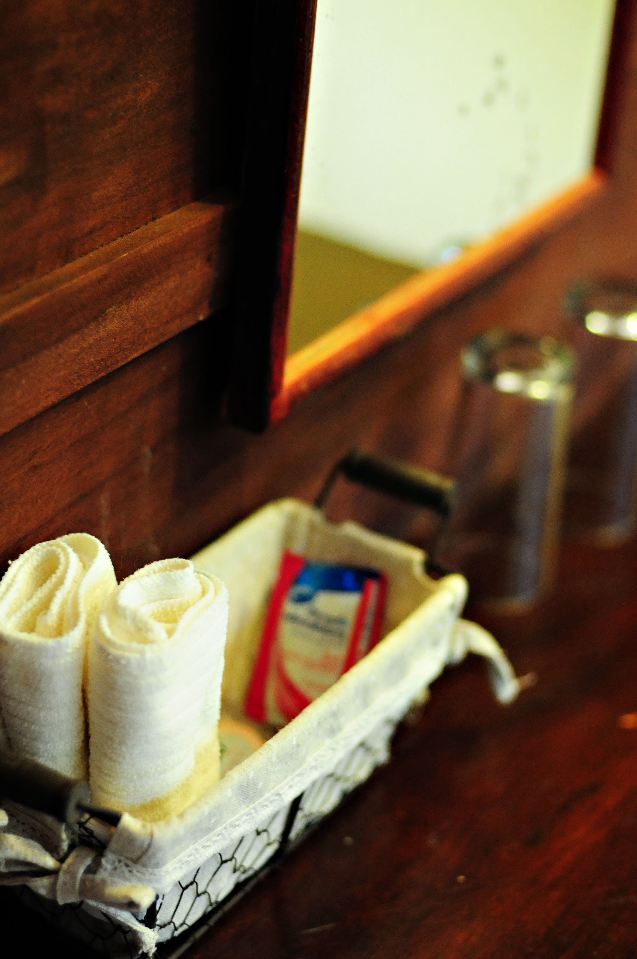 A wooden counter with a tray containing rolled towels and a box of tissues.