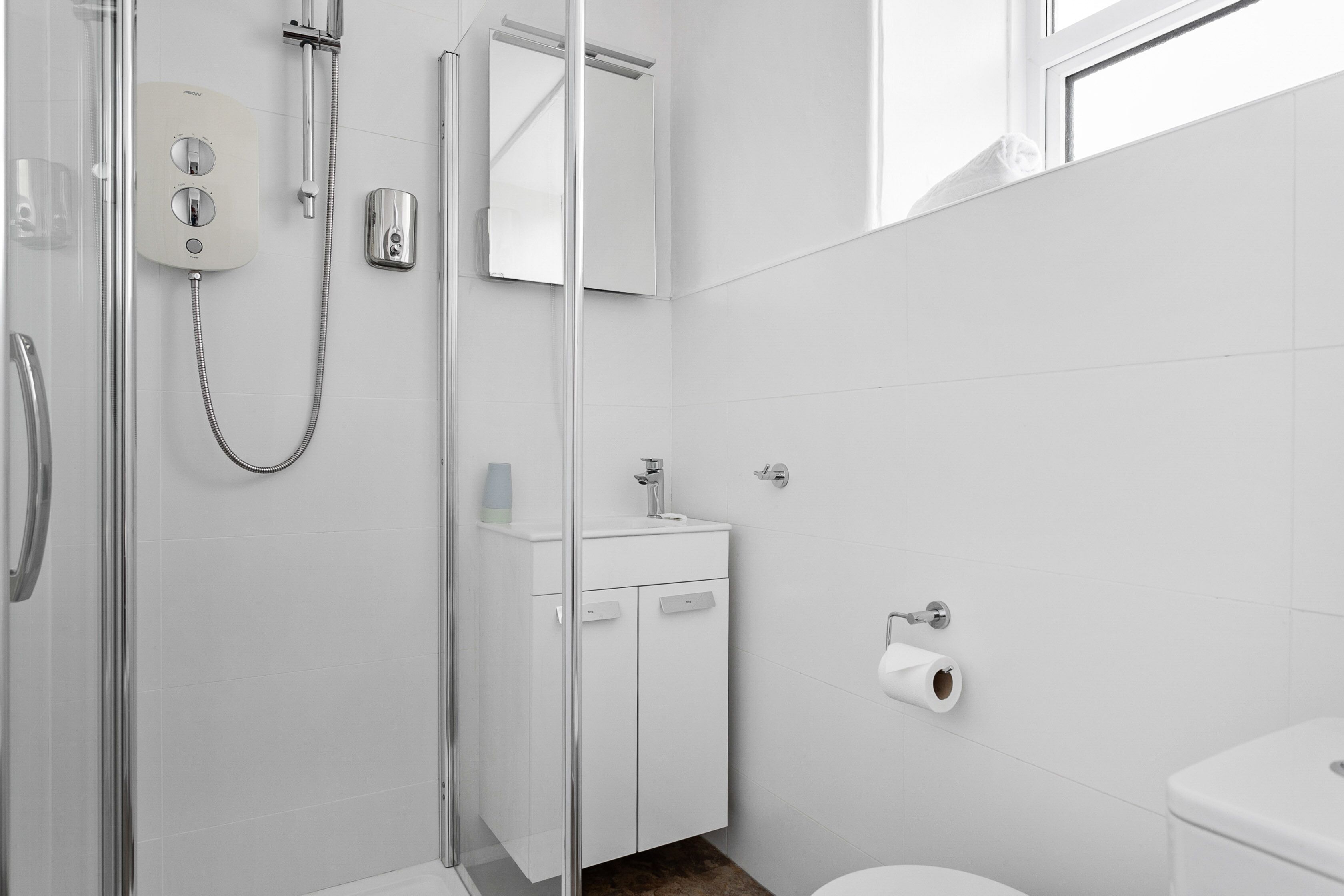 A modern bathroom with a glass shower enclosure, a white sink, and a toilet.