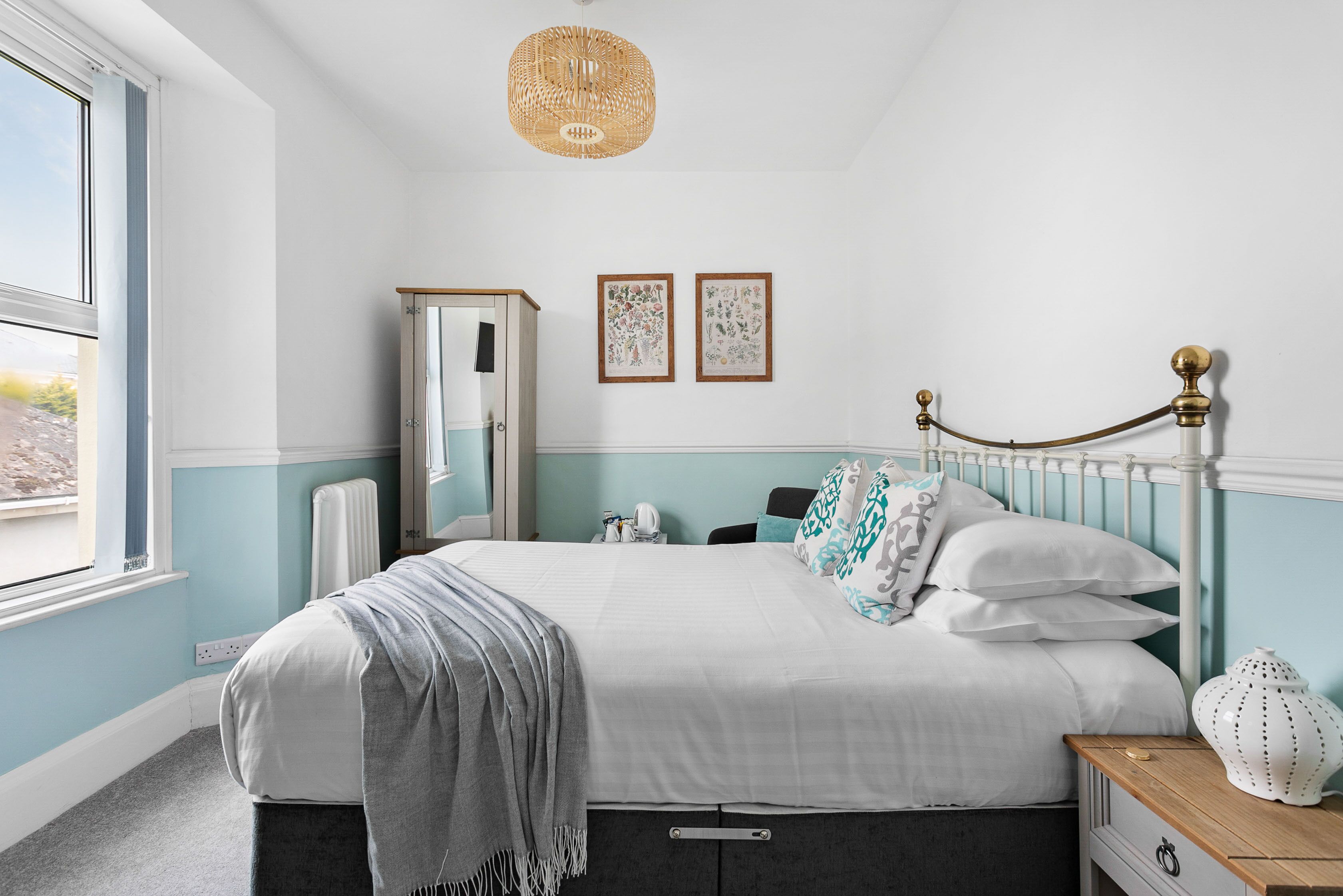 Ein Schlafzimmer mit Bett, Nachttisch, Schminktisch und Fenster.