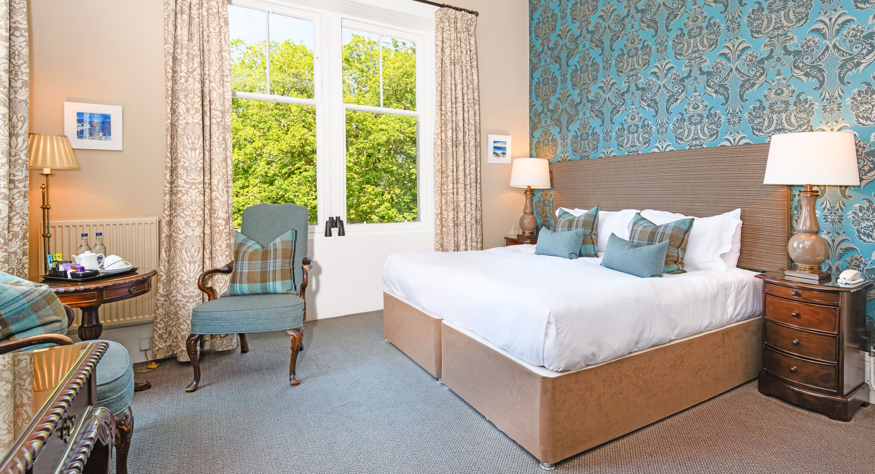 A bedroom with a large bed, a chair, a dresser, and a window with curtains.