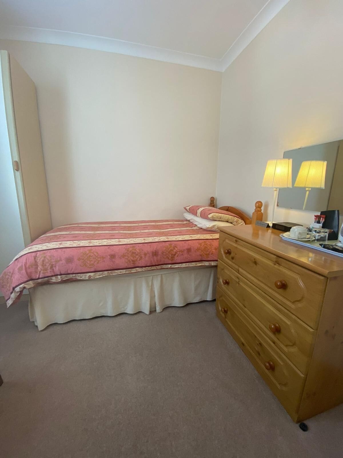 A bedroom with a bed, a dresser, and two bedside lamps.