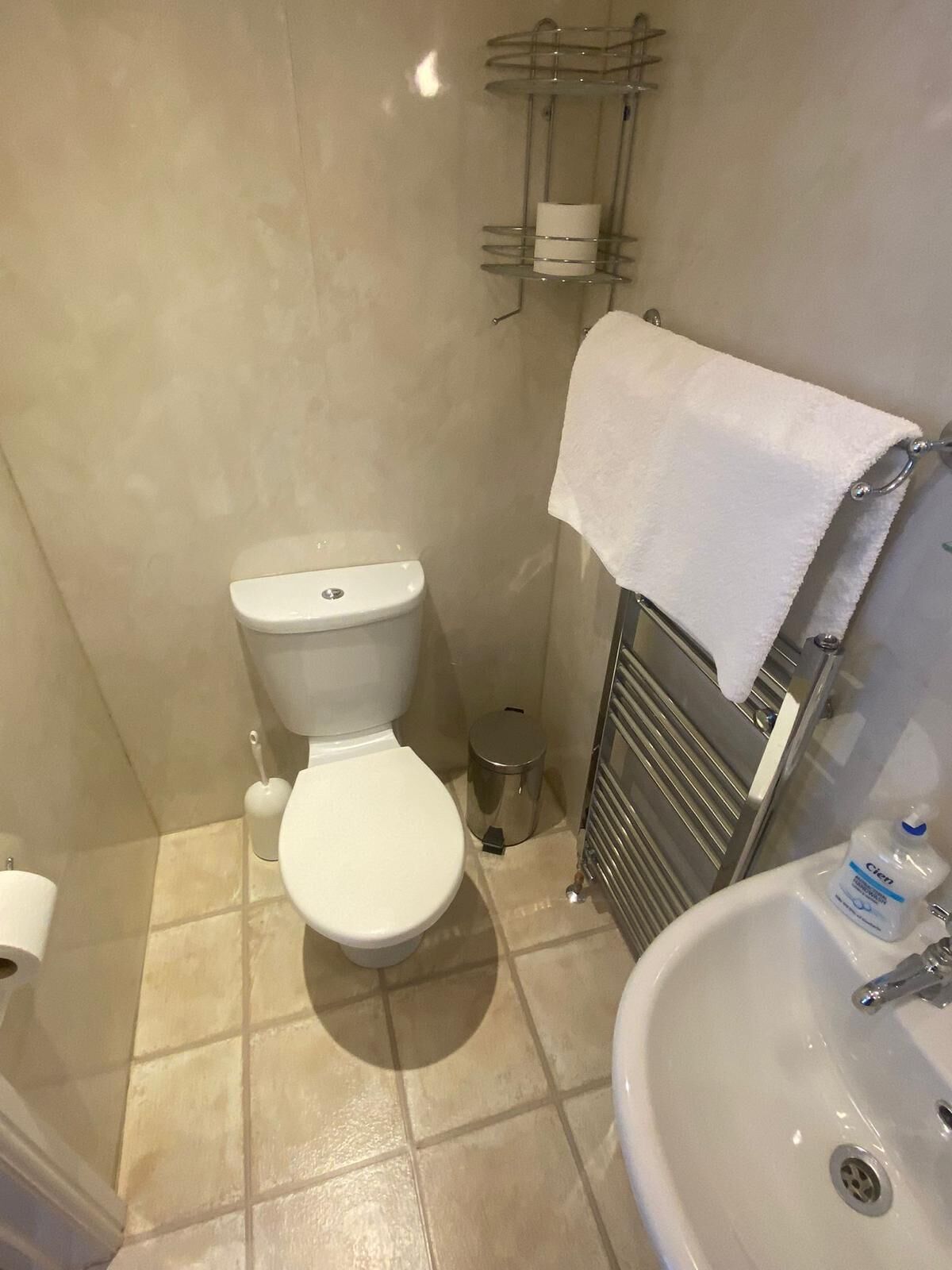 A small bathroom with a toilet, a sink, and a towel rack.