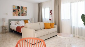 A modern hotel room with a bed, a sofa, a small table, and a chair. - Bluesea Cabo de Baños (Ciutadella de Menorca)