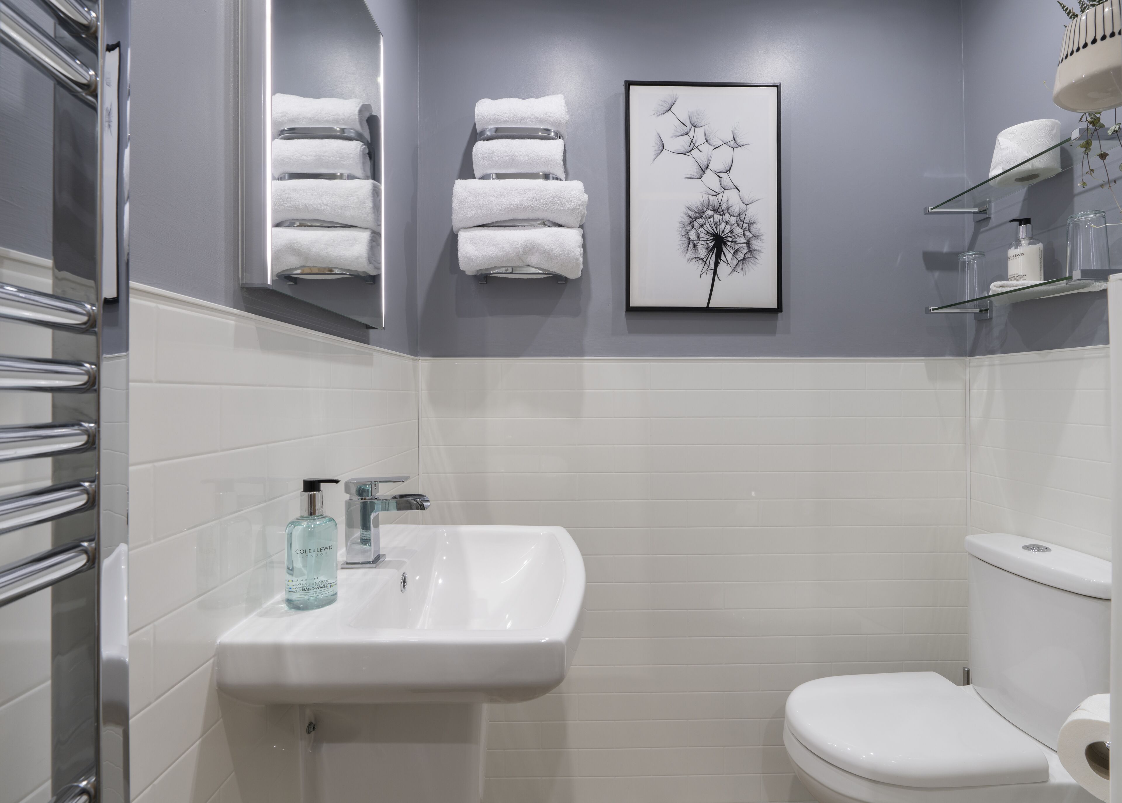 A modern bathroom with a white sink, a toilet, and a framed artwork above the sink.