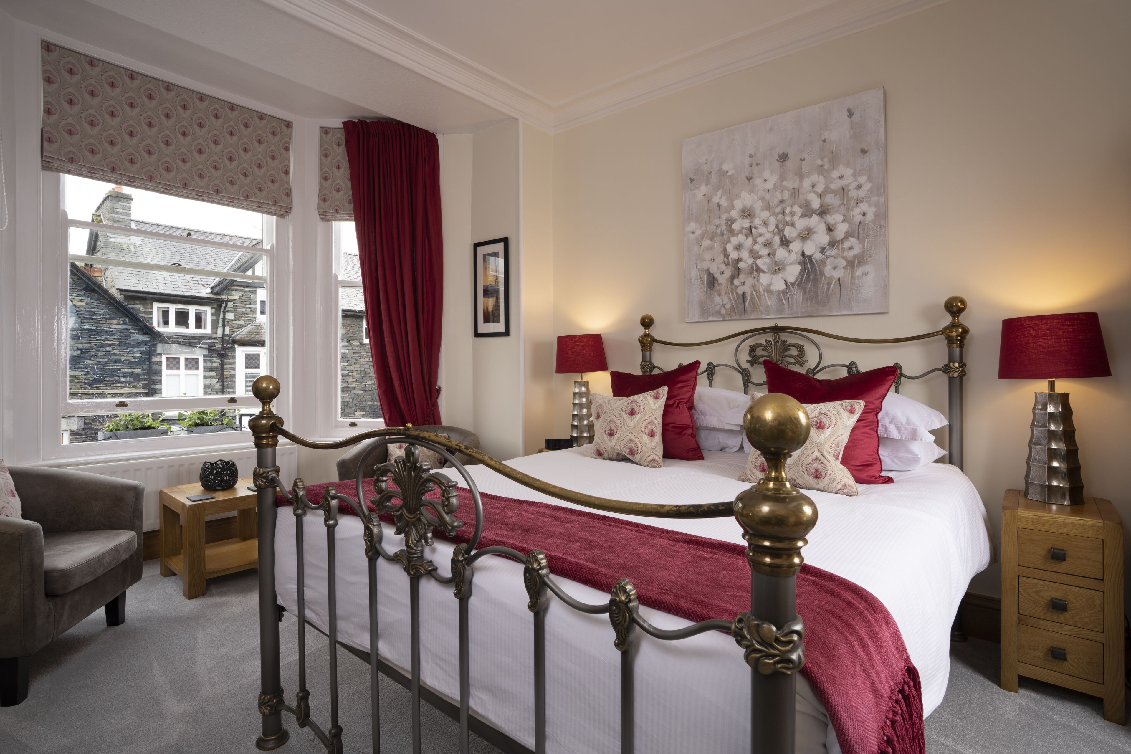 Une chambre à coucher avec un grand lit, une table de chevet, une chaise et une fenêtre donnant sur des immeubles.