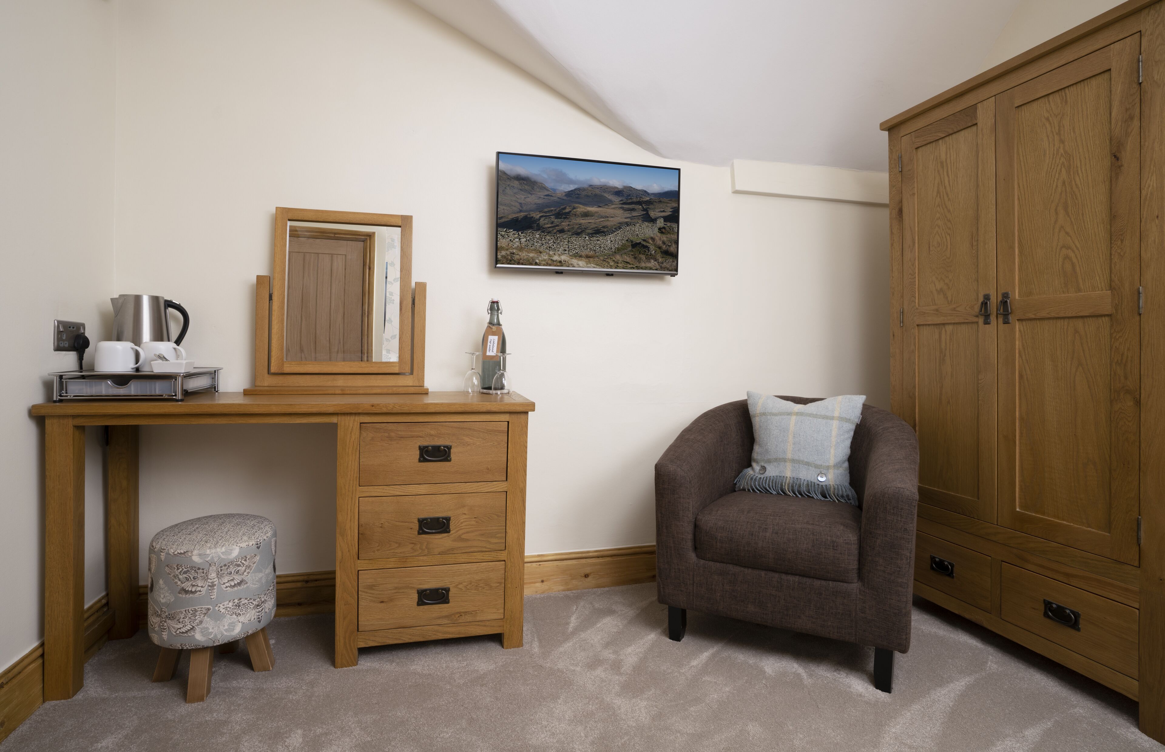 Ein Schlafzimmer mit Holzschreibtisch, Stuhl, Kleiderschrank und einem gerahmten Bild an der Wand.