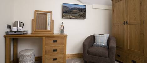 A bedroom with a wooden desk, a chair, a wardrobe, and a framed picture on the wall.